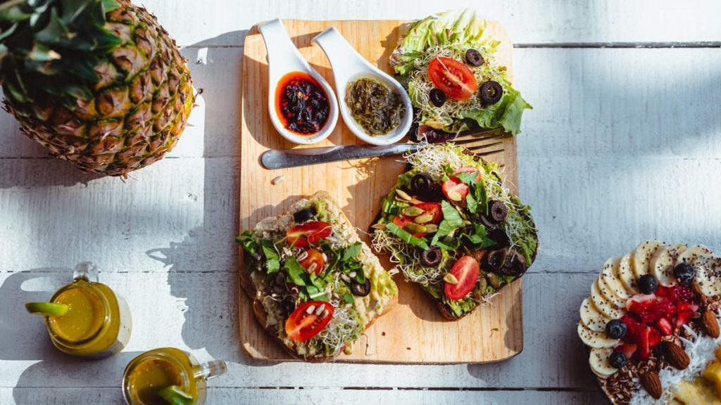 Top view of a vibrant and healthy brunch spread with sandwiches, fruits, and juices on a wooden table.
