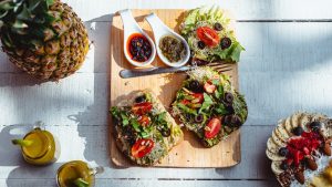 Top view of a vibrant and healthy brunch spread with sandwiches, fruits, and juices on a wooden table.